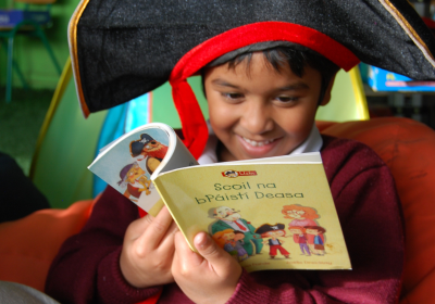 Child reading book in Irish language at the launch of the An Bosca Leabharlainne project