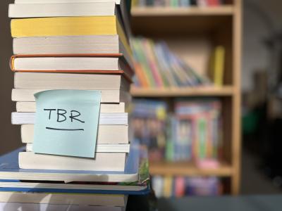 Stack of books with a 'TBR' post-it note attached