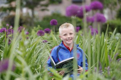 Ned McCarthy 2025 Reading Hero in a flower bed with book