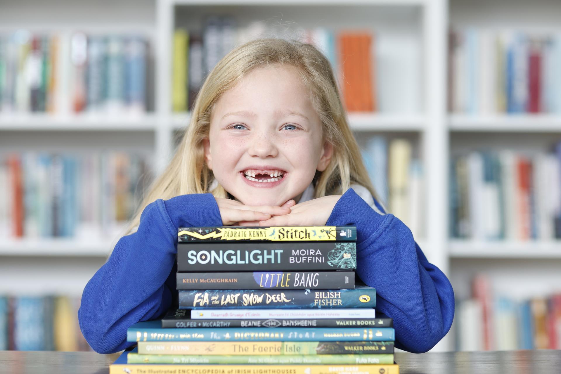 Girl smiling and resting head on a pile of books