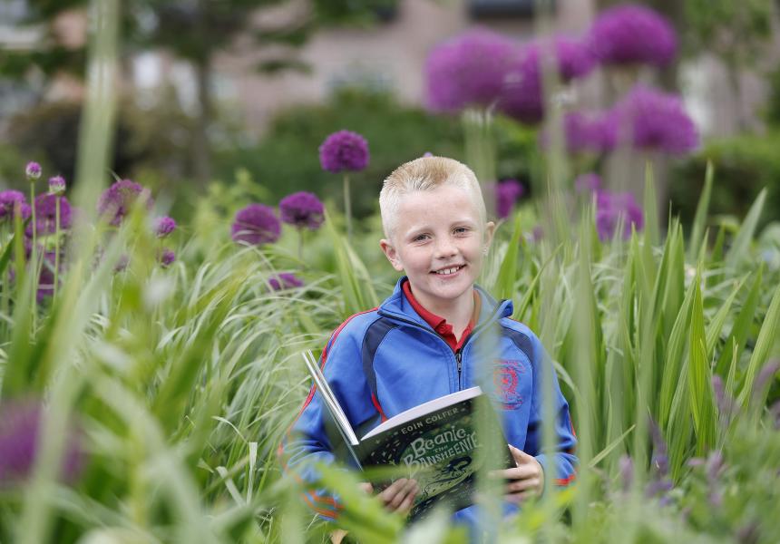 Ned McCarthy 2025 Reading Hero in a flower bed with book