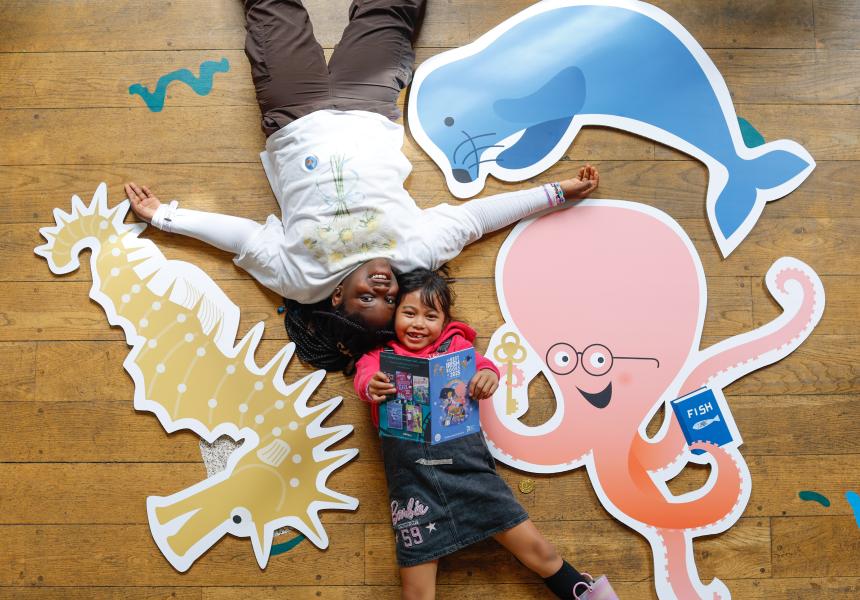 Two girls on the floor with sea creatures, one girl holding the Best Irish Books toward the camera