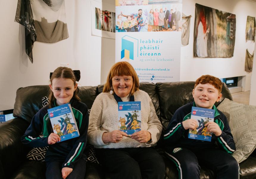 students sitting on sofa with Patricia Forde, all holding reading guides