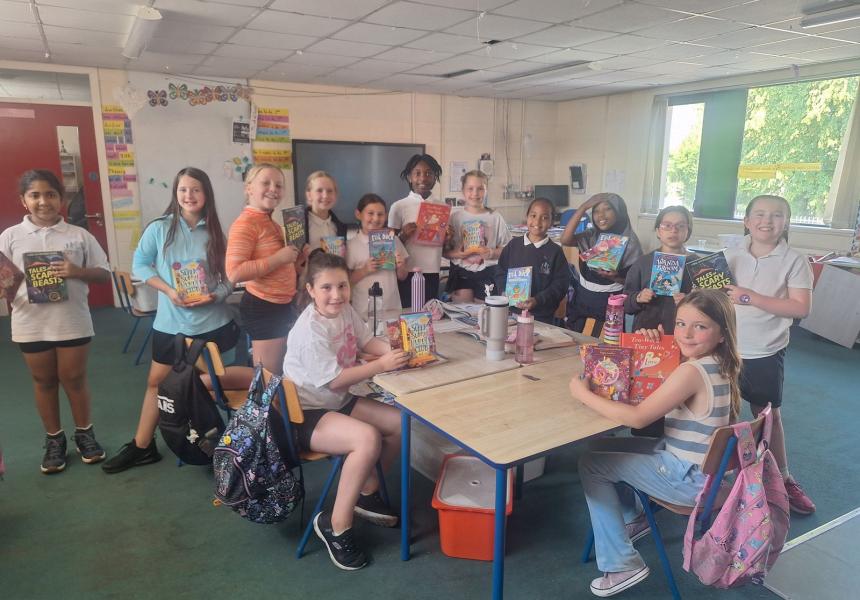 Children around a table in the classroom with books